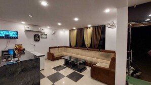 A modern living room with a sofa, a glass coffee table, a TV, and a reception desk. - Sunrise Palace (Pushkar)