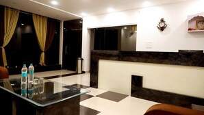 A modern hotel lobby with a glass table, check-in counter, and seating area. - Sunrise Palace (Pushkar)