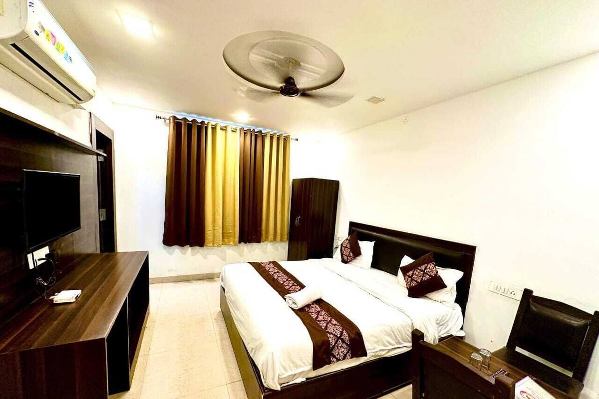 Une chambre d’hôtel équipée d’un lit, d’une table de chevet, d’une télévision et d’un ventilateur de plafond.