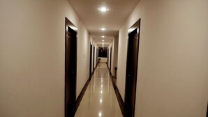 A long, narrow hotel corridor with doors on both sides and a shiny tiled floor. - Sunrise Palace (Pushkar)