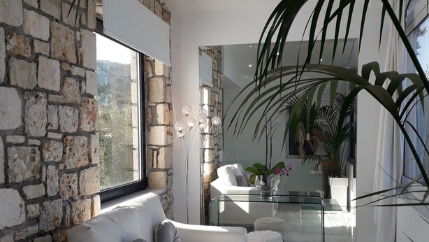 A modern living room with a stone wall, a white sofa, and a glass coffee table. - Dion Suite And Spa In Zakynthos (Zakynthos)