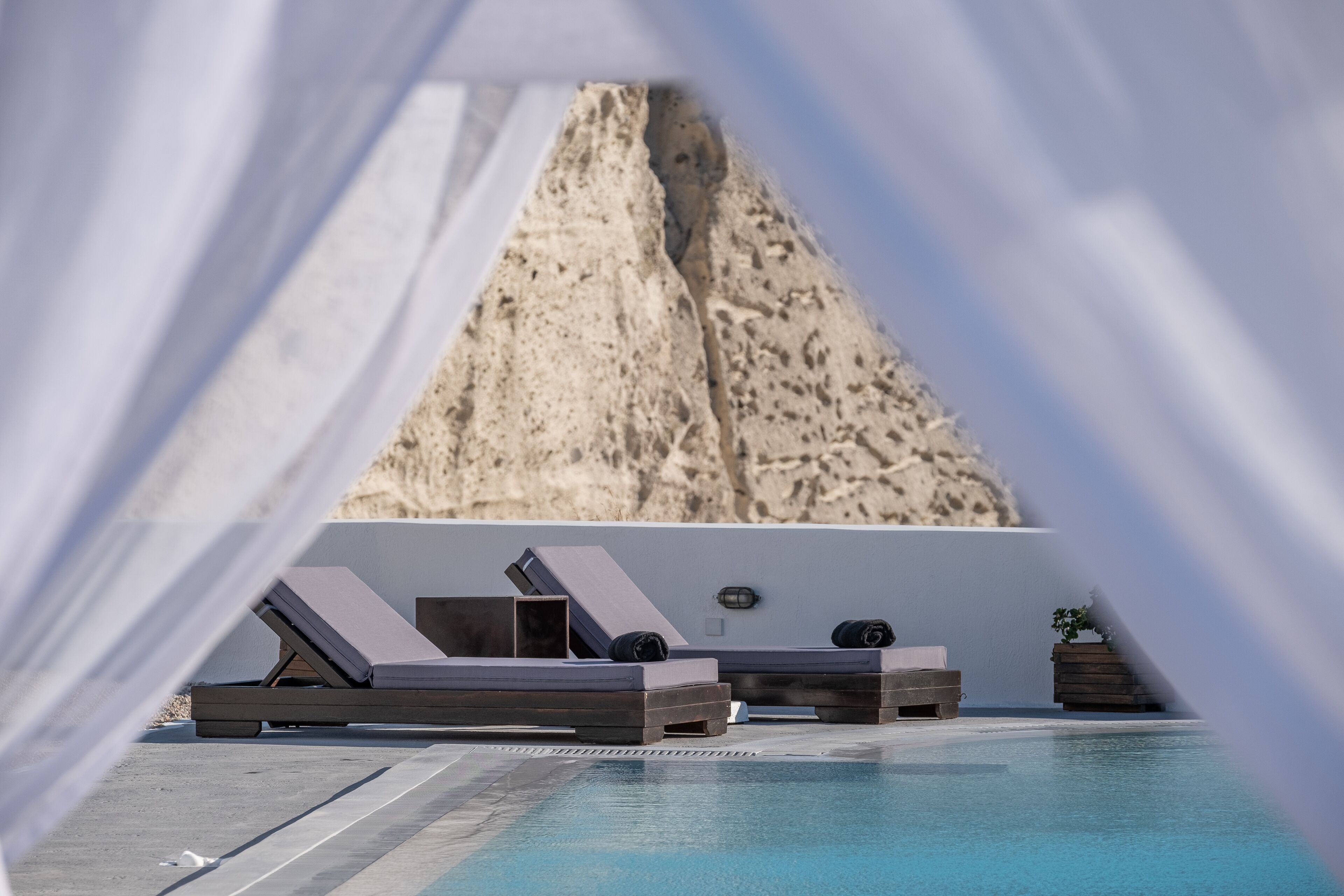 A poolside area with lounge chairs and a view of a rocky landscape.