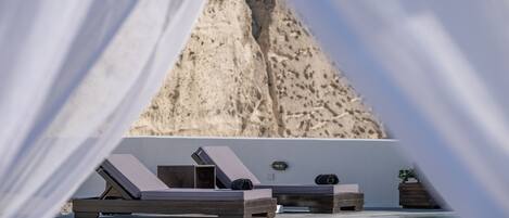 A poolside area with lounge chairs and a view of a rocky landscape.