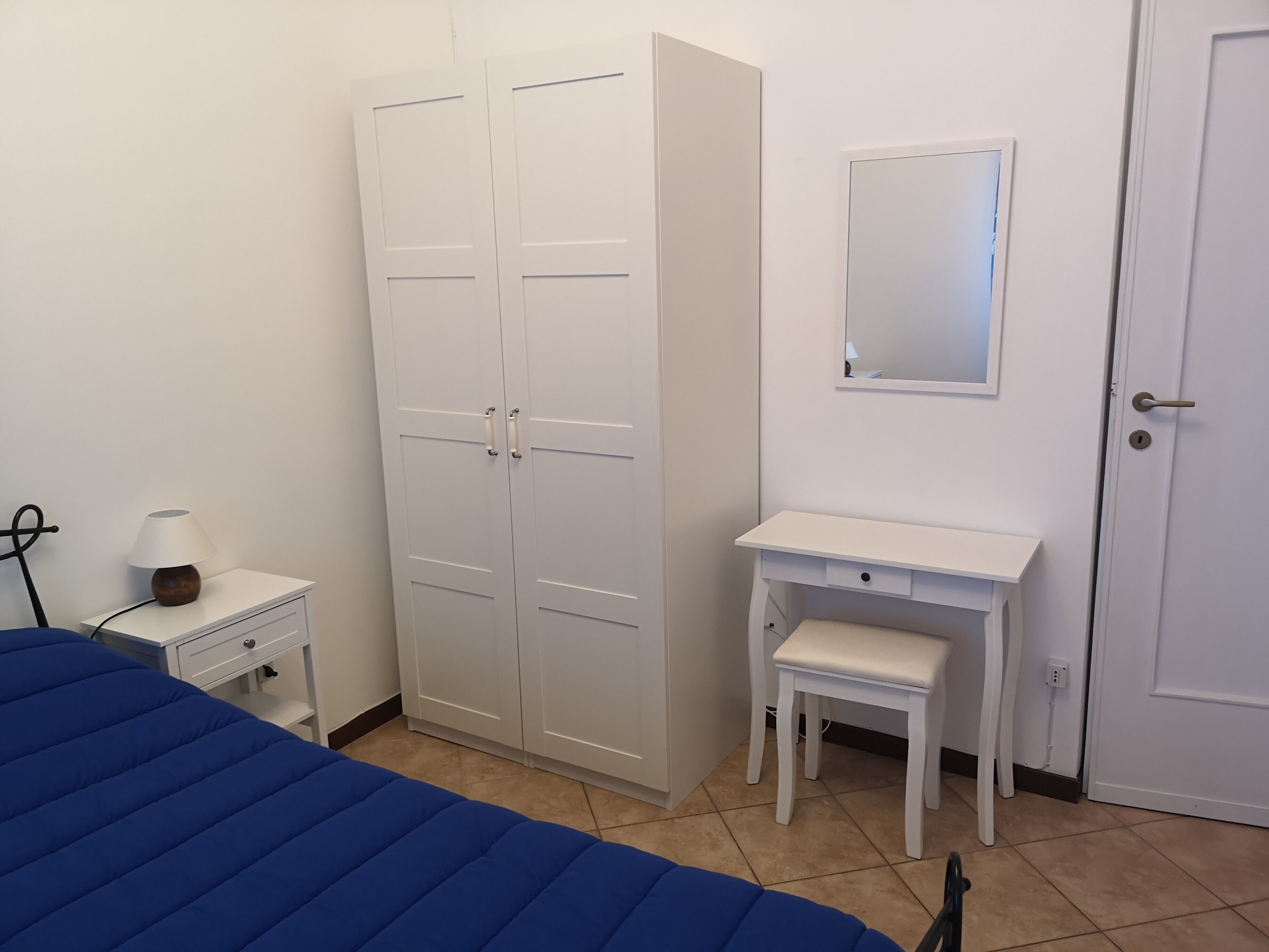 Une chambre à coucher comprenant un lit, une armoire, un bureau et un miroir.