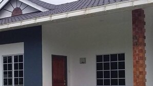 Una casa de dos pisos con un porche, una columna de ladrillo y un pequeño jardín.