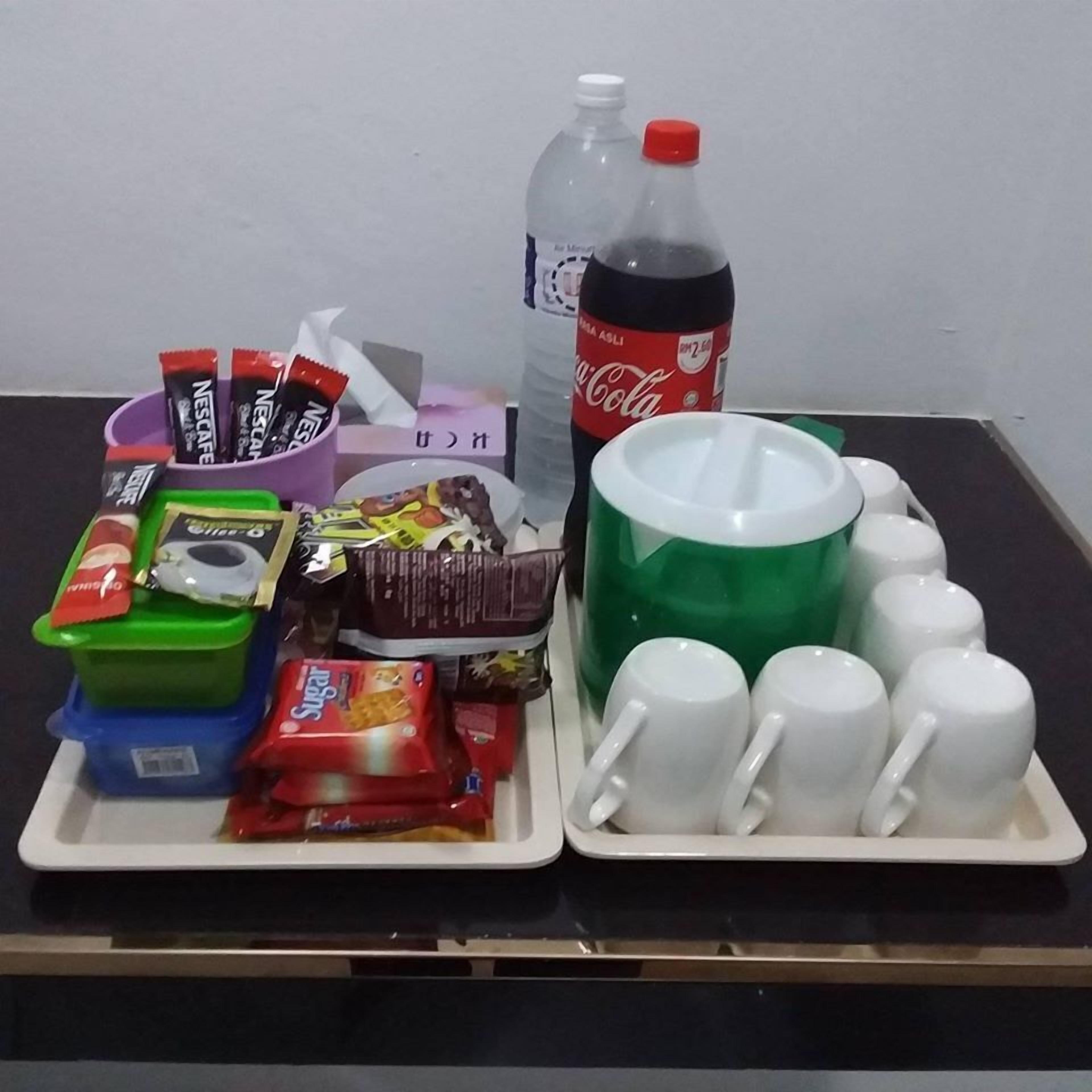 A tray with snacks, a Coca-Cola bottle, and white mugs on a table.