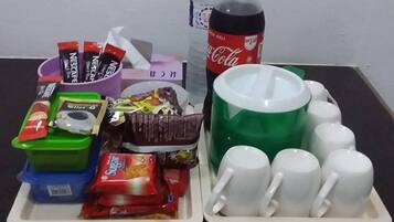A tray with snacks, a Coca-Cola bottle, and white mugs on a table.