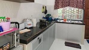 Una cocina compacta con estufa a gas, una olla arrocera y un lavamanos.