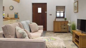 Un salon avec un canapé, un meuble en bois, une télévision et une fenêtre.