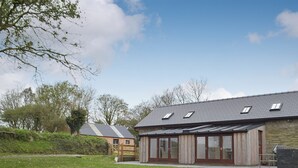 Un bâtiment moderne doté d’un toit en pente, de grandes fenêtres et d’un espace verdoyant à l’avant.