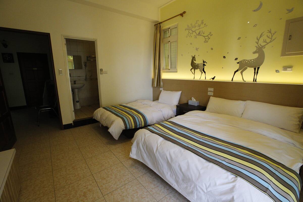 A hotel room with two beds, a bathroom, and a wall decorated with animal decals.