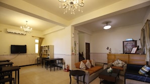 A living room with a sofa, coffee table, and dining area with chairs and a table. - Hai Bin Minsu (Jinning)