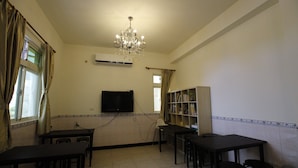 A dining area with tables and chairs, a chandelier, a television, and a bookshelf. - Hai Bin Minsu (Jinning)