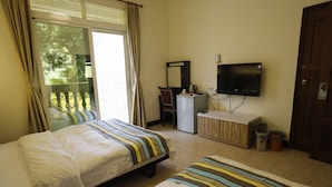 A hotel room with two beds, a desk, a television, and a sliding glass door to the outside. - Hai Bin Minsu (Jinning)