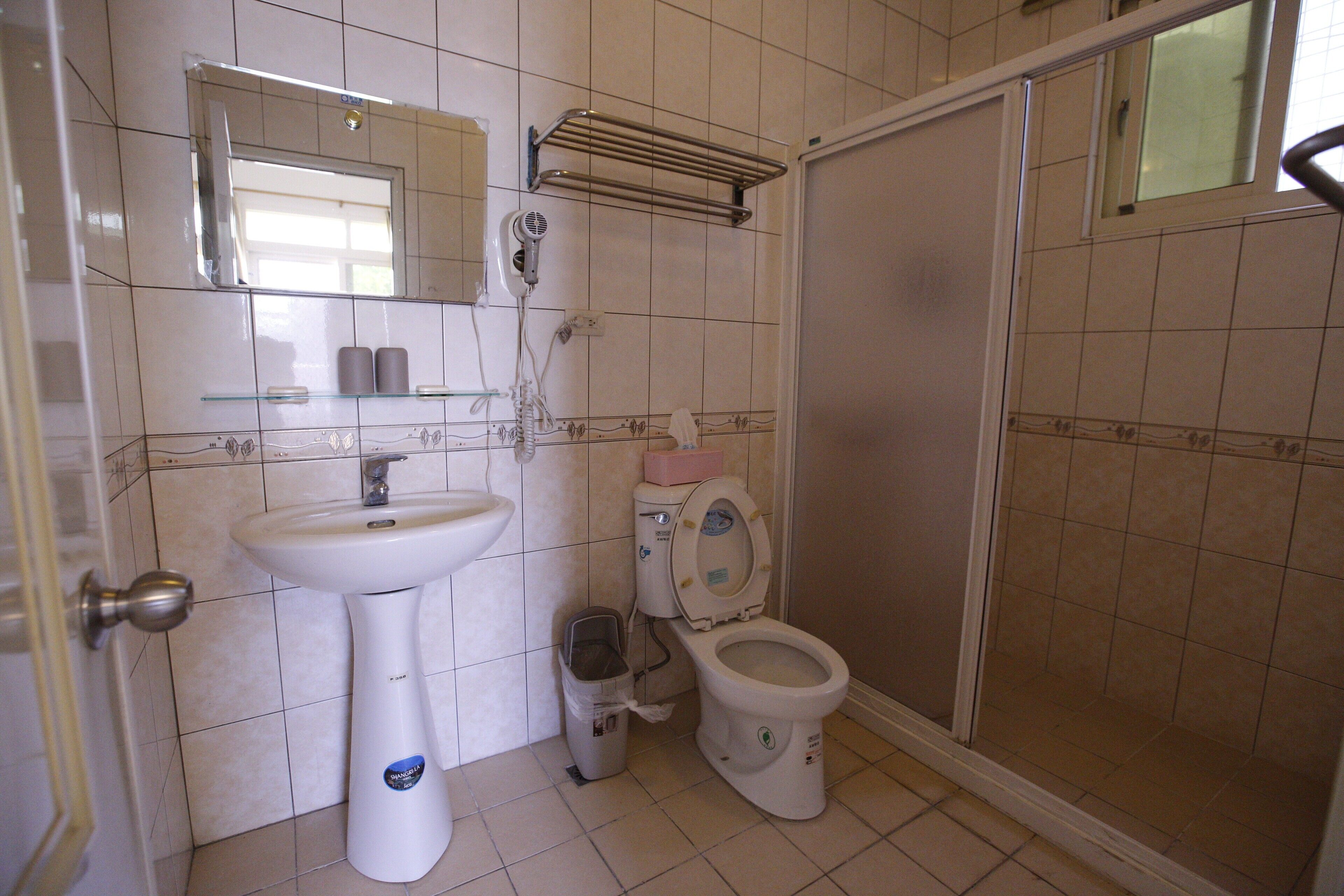 Un baño con lavamanos, inodoro y zona de ducha.