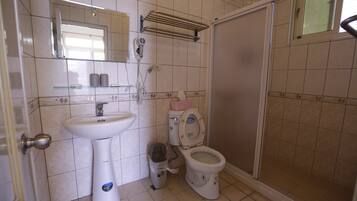 Un baño con lavamanos, inodoro y zona de ducha.