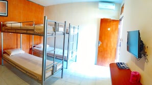 A bunk bed room with a wooden door, a television, and a red object on a wooden table. - Griya Alisha (Sleman)