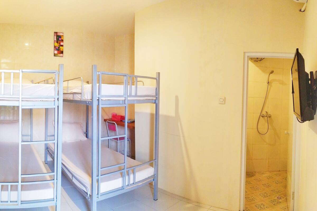 A room with bunk beds, a shower, and a small shelf with items.