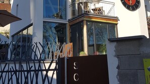 Een modern gebouw met twee verdiepingen, een balkon, een klok en een bord waarop 'SCHMUCKASTEL' staat.