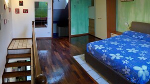 Ein Schlafzimmer mit einem Bett, einem Kleiderschrank, einem Schreibtisch und einer Treppe.