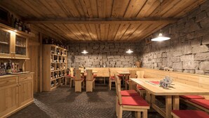 A rustic wooden interior with stone walls, wooden tables and benches, and shelves with bottles. - Hotel Torgglhof Kaltern (Caldaro Sulla Strada del Vino)