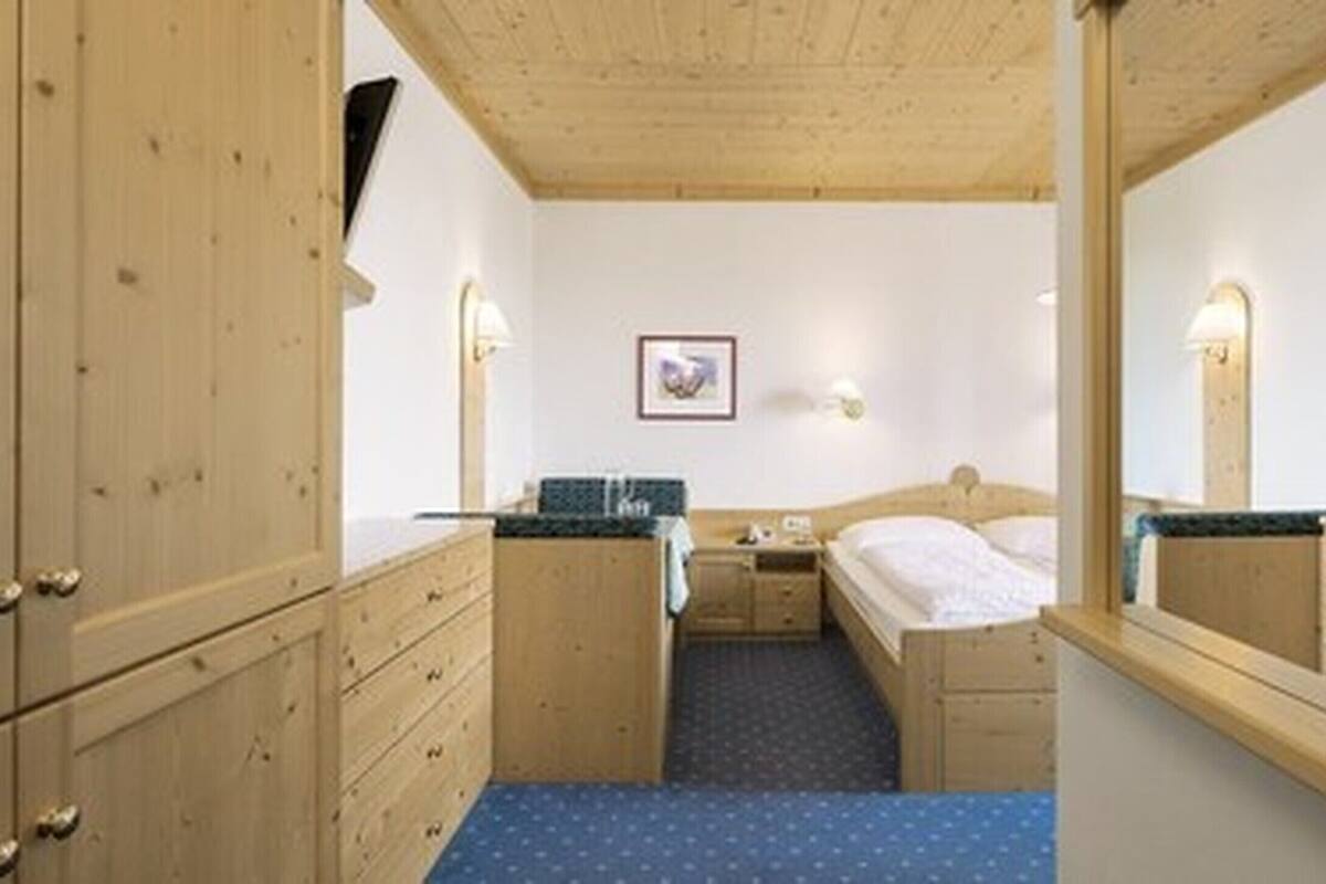 Una habitación con armarios de madera, una cama, una mesita y un espejo.