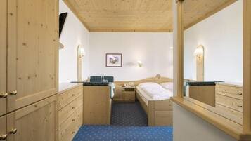 A room with wooden cabinets, a bed, a small table, and a mirror.