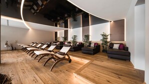 A modern spa with wooden flooring, lounge chairs, and sofas arranged for relaxation. - Hotel Torgglhof Kaltern (Caldaro Sulla Strada del Vino)