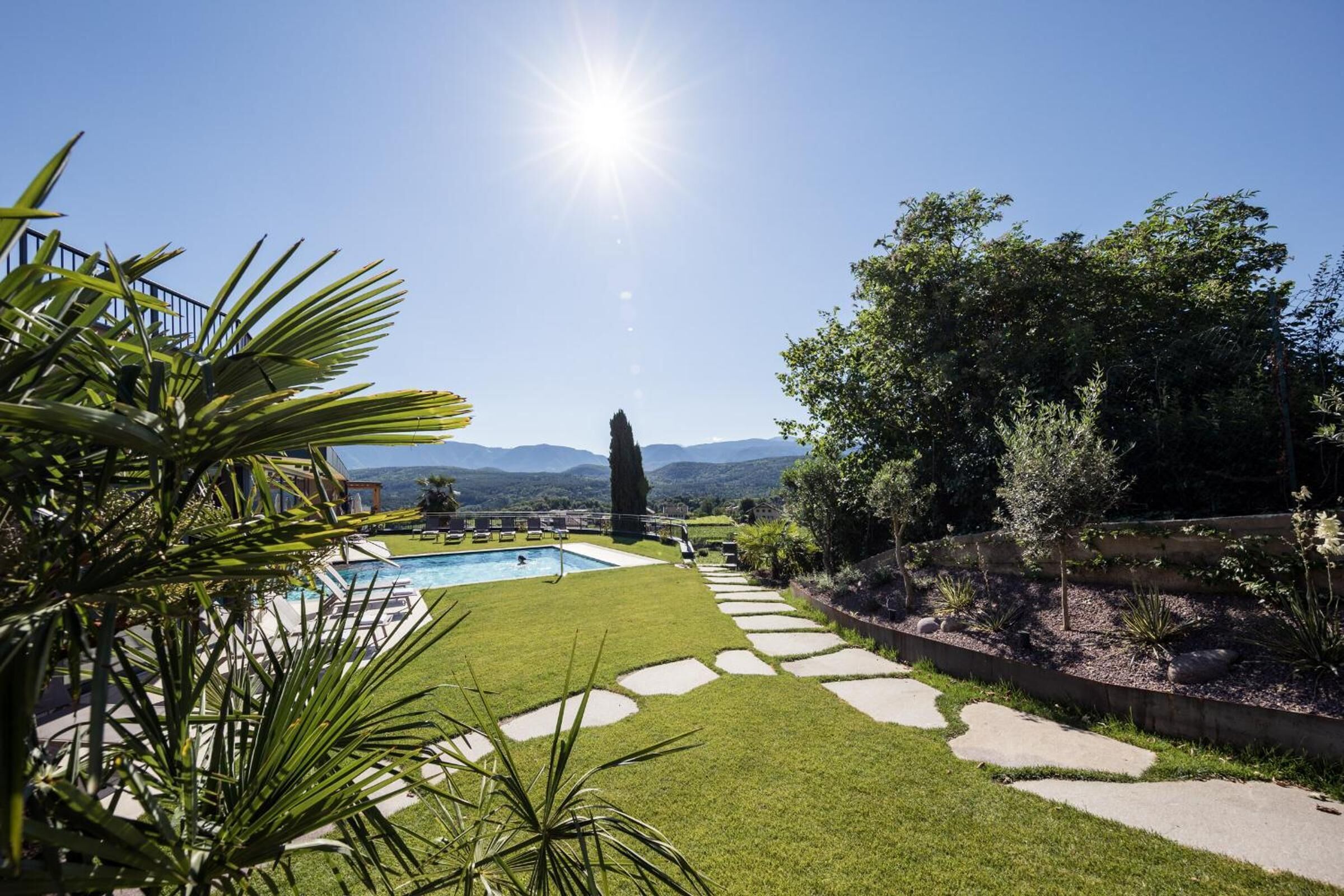 A backyard with a swimming pool, stone pathway, and a view of mountains.