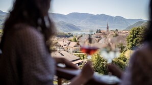 A view of a town with mountains in the background, a church with a tall tower, and a lake. - Hotel Torgglhof Kaltern (Caldaro Sulla Strada del Vino)