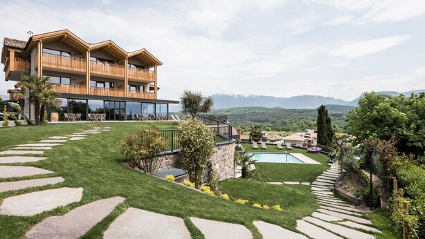 A two-story building with balconies, a swimming pool, and a well-maintained lawn with stone pathways. - Hotel Torgglhof Kaltern (Caldaro Sulla Strada del Vino)