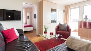 A modern living room with a glass coffee table, leather sofas, a red rug, and a large TV. - Wonderful view for 4 people 100 m from the main beach (Wangerooge)