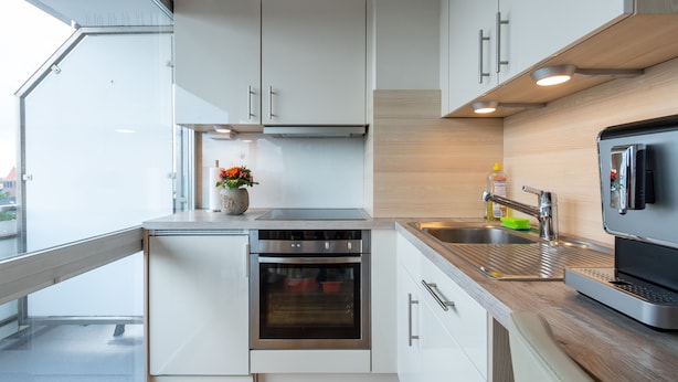 A modern kitchen with white cabinets, a stainless steel oven, a sink, and a built-in microwave. - Wonderful view for 4 people 100 m from the main beach (Wangerooge)