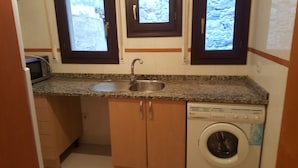 A compact kitchen with a built-in sink, a microwave, and a washing machine. - Beautiful duplex in unbeatable location (Segovia)
