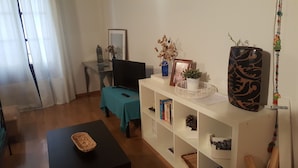 A living room with a TV, a bookshelf, a coffee table, and a decorative vase. - Beautiful duplex in unbeatable location (Segovia)
