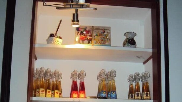 A shelf with various bottles and a clock. - Hotel Mirage (Messina)