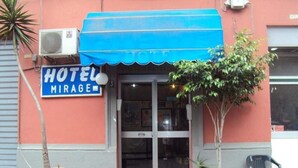 A hotel entrance with a blue awning, a sign reading "HOTEL MIRAGE," and two potted plants. - Hotel Mirage (Messina)