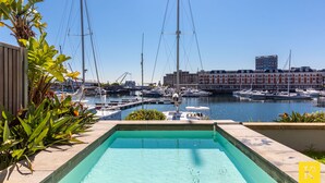 Une piscine avec vue sur un port de plaisance et des bâtiments en arrière-plan.