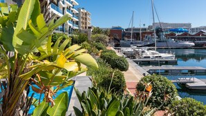 Un port de plaisance où sont amarrés des bateaux, entouré d’une végétation luxuriante et de bâtiments modernes.