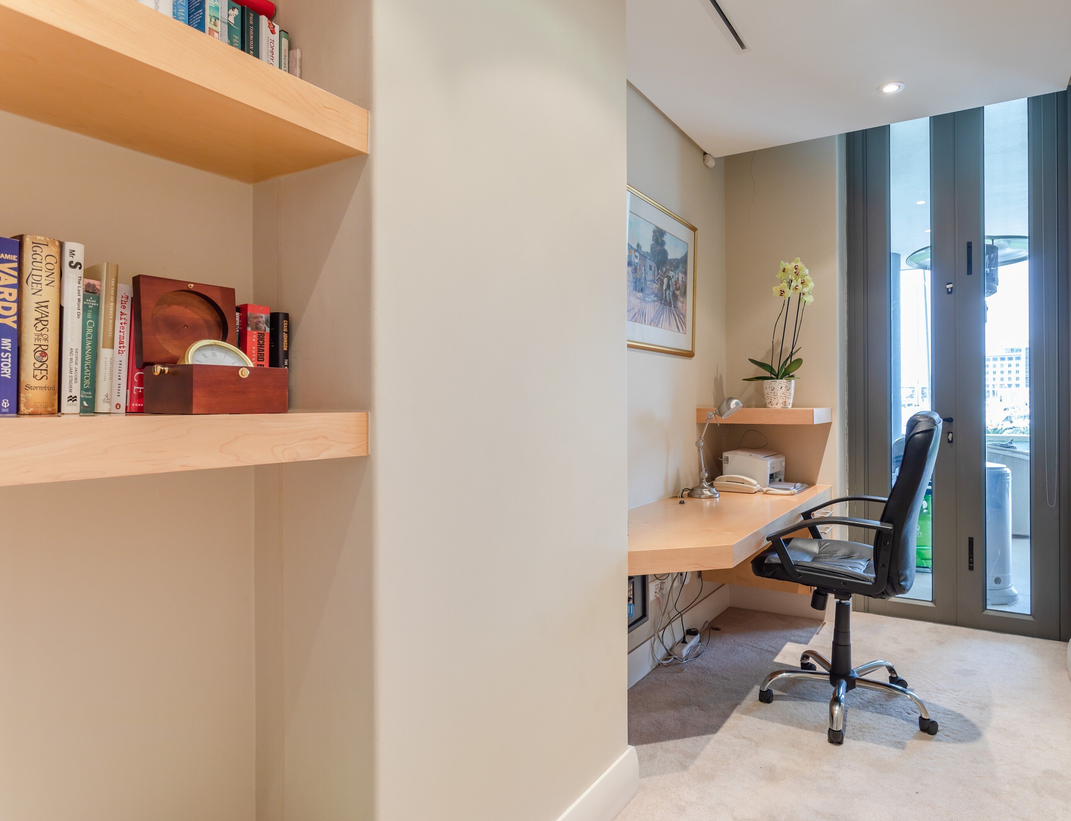 Un espacio de oficina moderno con escritorio, silla, estantería y ventana con vista a la ciudad.