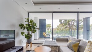 Uma sala de estar moderna com uma janela grande, um sofá, uma mesa de centro e uma televisão.