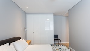 A modern bedroom with a bed, a wardrobe, a desk, and a chair. - 202 Warwick (Cape Town)