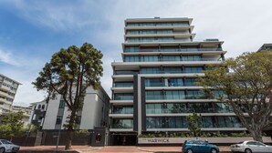 Um edifício de vários andares com design arquitetônico moderno, apresentando uma entrada imponente com uma placa que diz 'THE WARWICK'.