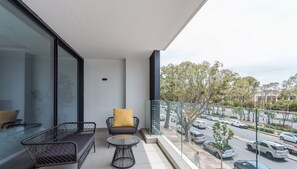 Un balcon avec une porte-fenêtre, un canapé, une chaise et une petite table.