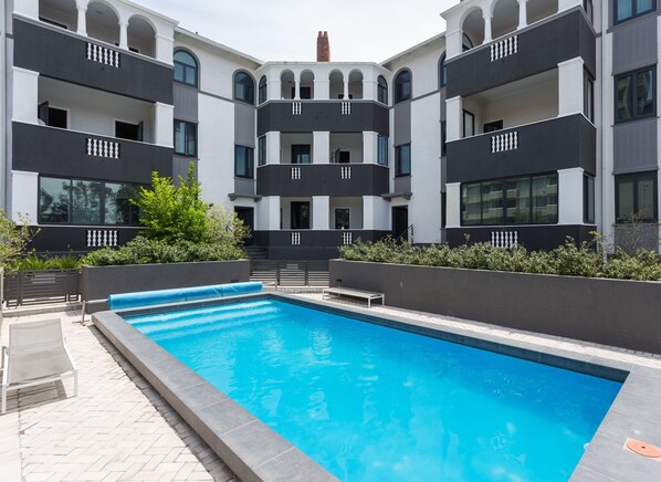 A modern building with a swimming pool, balconies, and a brick chimney. - 202 Warwick (Cape Town)