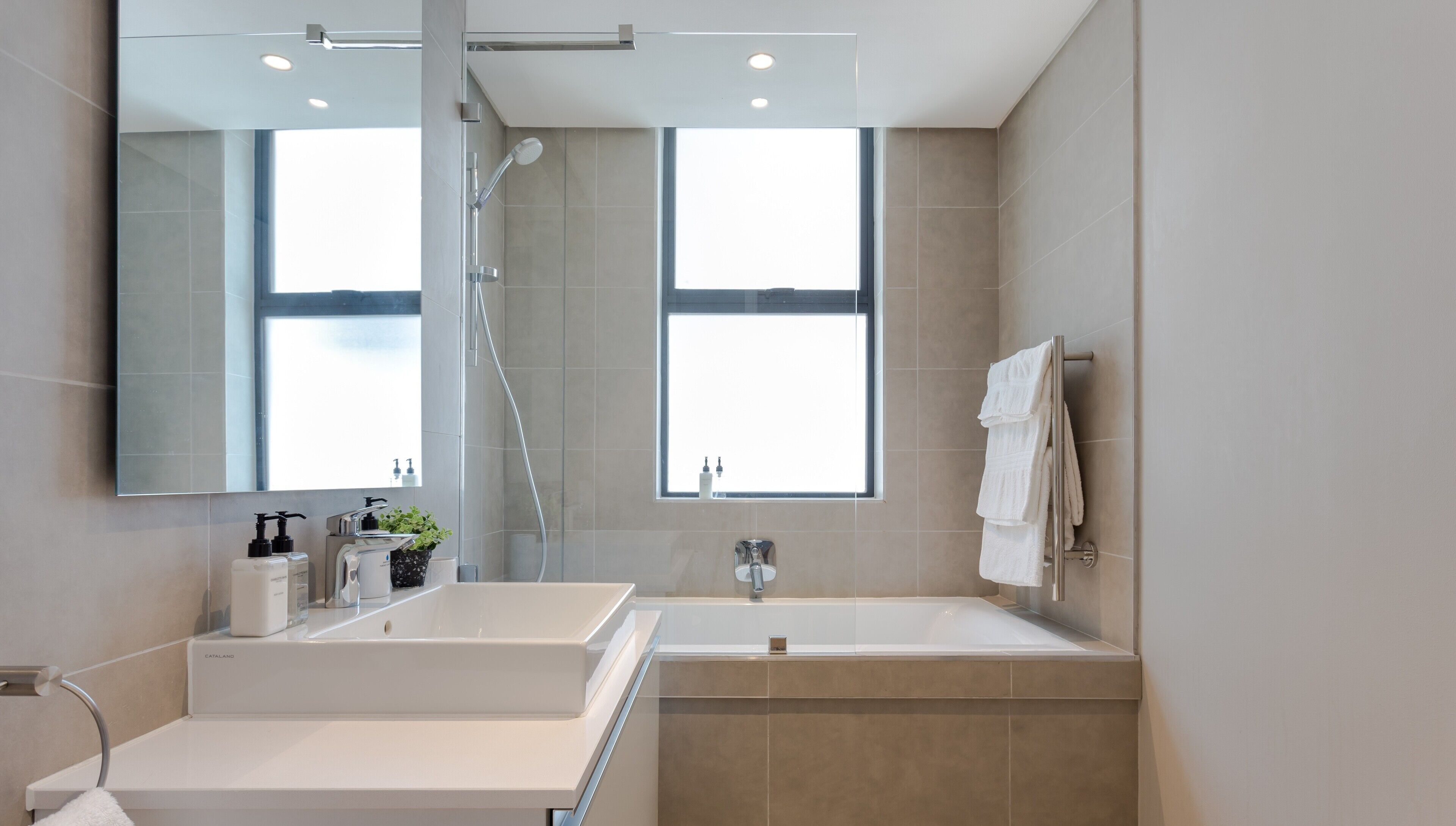Ein modernes Badezimmer mit zwei Waschbecken, einem großen Spiegel und einer Dusche.