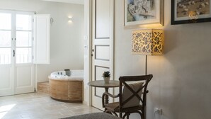Een kamer met een houten kast, een ronde tafel met een stoel, een wandlamp en twee ingelijste foto's.