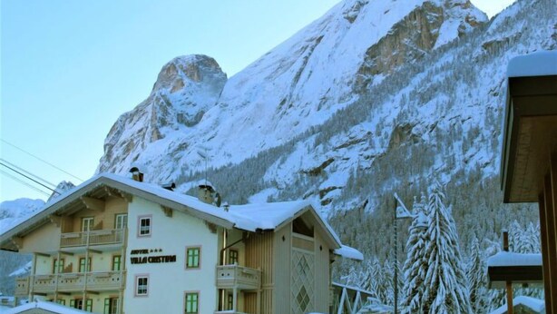Un immeuble à plusieurs étages doté de balcons, entouré de montagnes enneigées.