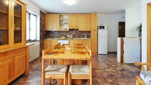 Une cuisine avec des meubles en bois, une table à manger avec des chaises, un four à micro-ondes et un réfrigérateur.