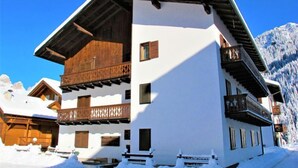 Un chalet à plusieurs étages, doté d’un toit à forte pente, de balcons en bois et surplombant un paysage enneigé.